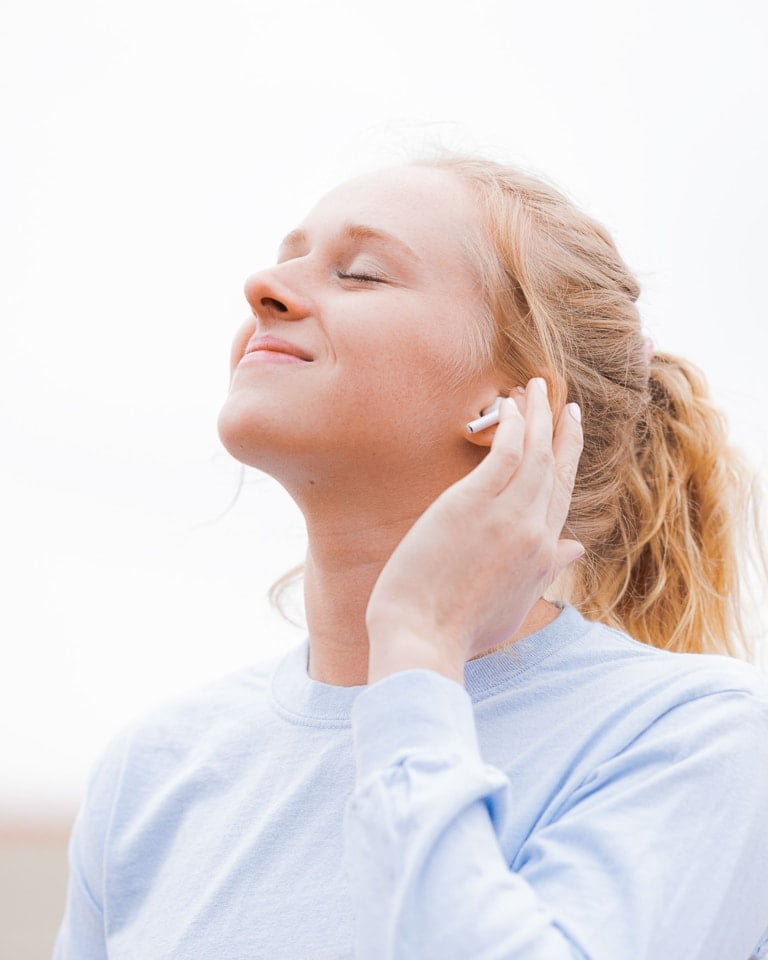 A woman wearing a blue t-shirt and earphones.