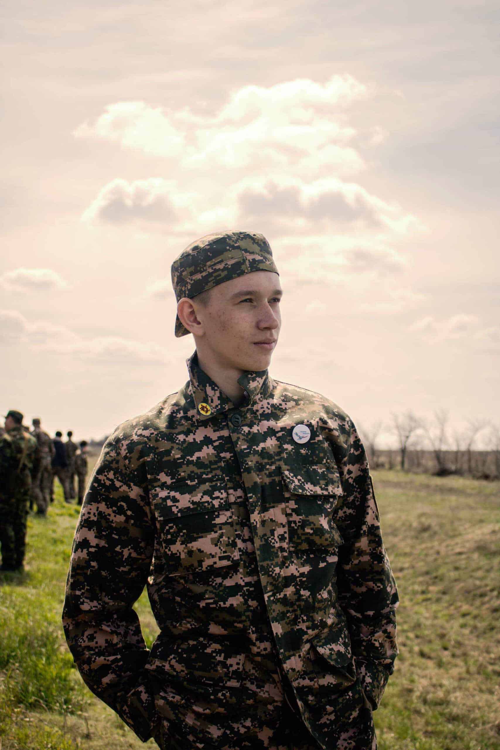 A man in a camouflage uniform standing in a field.