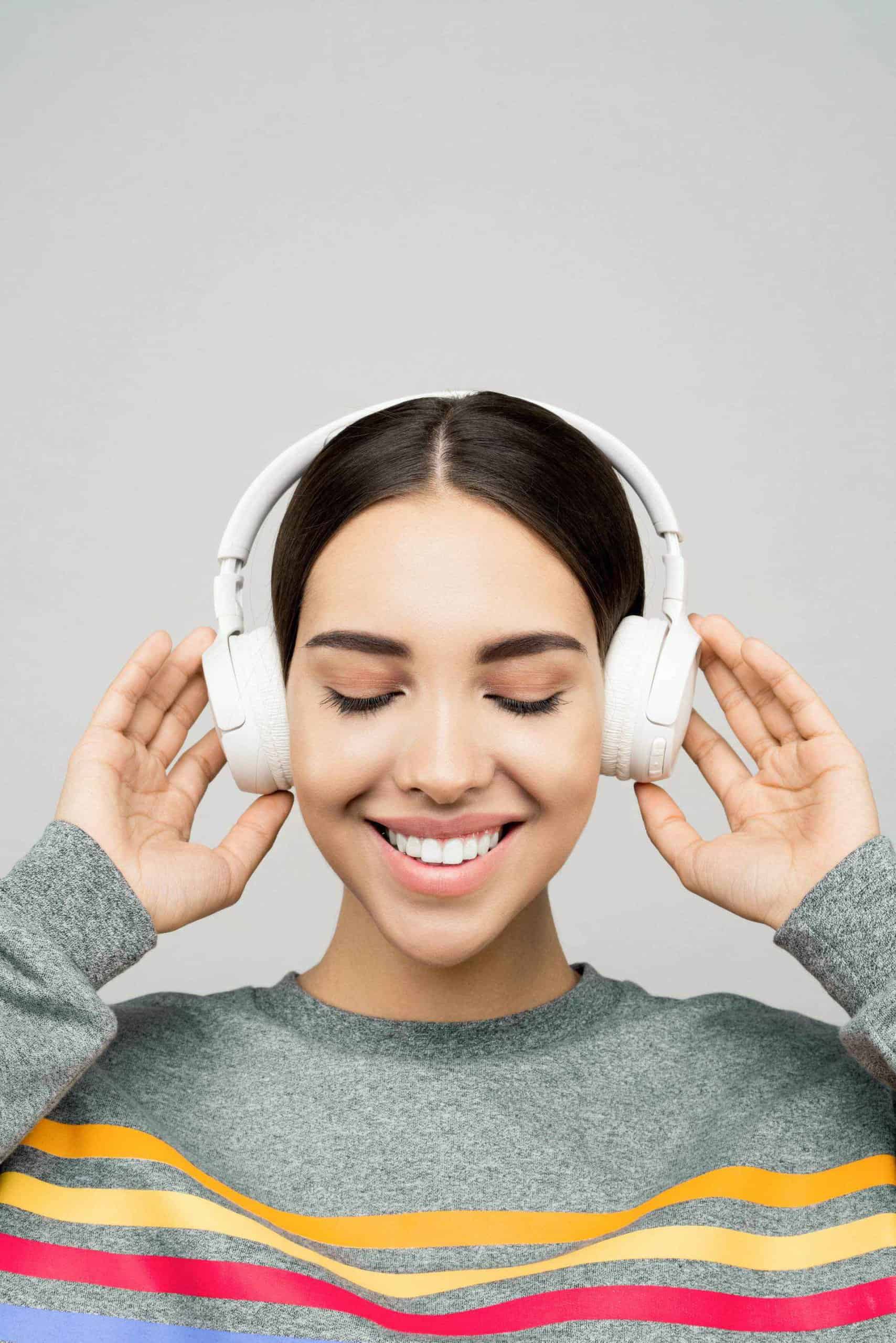 A young woman wearing headphones with her eyes closed.